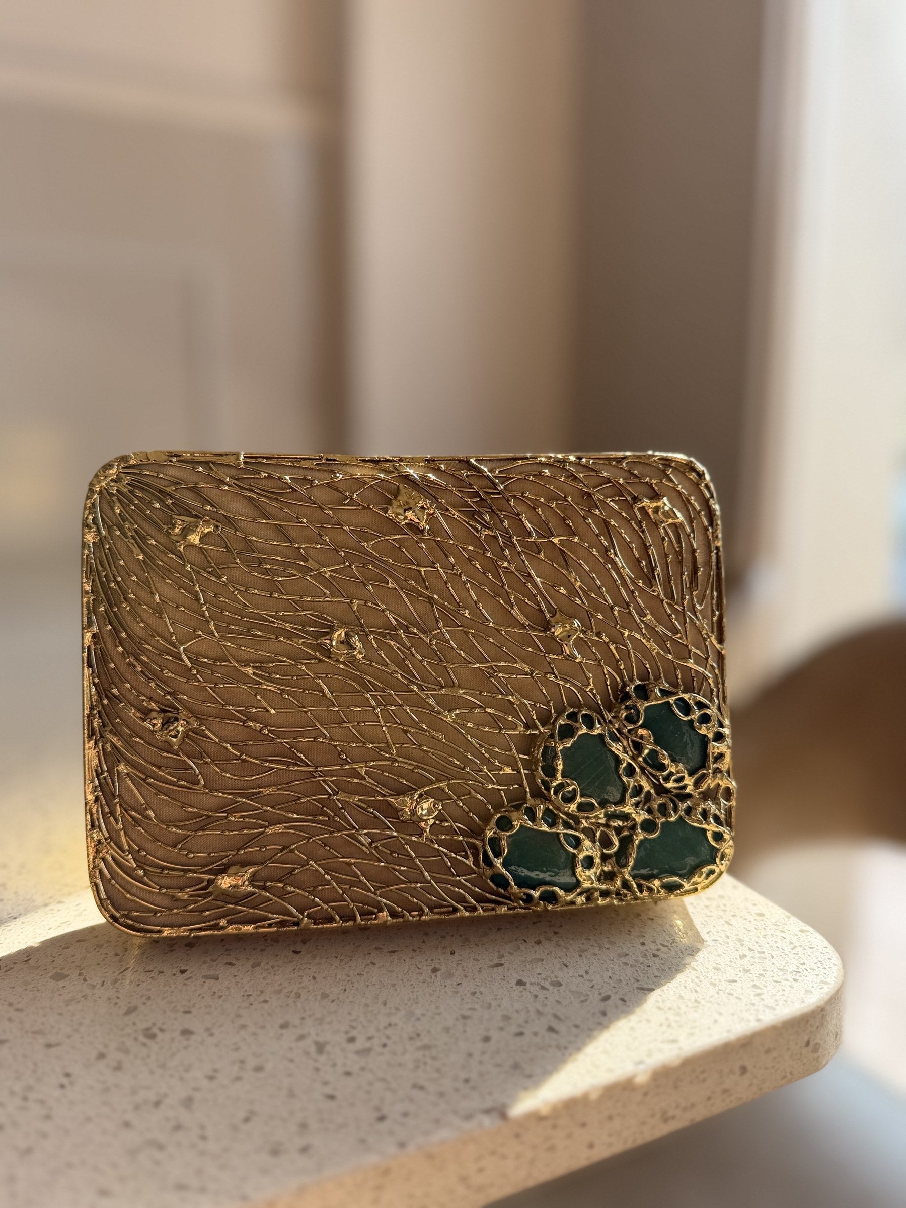 Detailed close-up of the emerald-green stones set on the polished gold brass canvas.