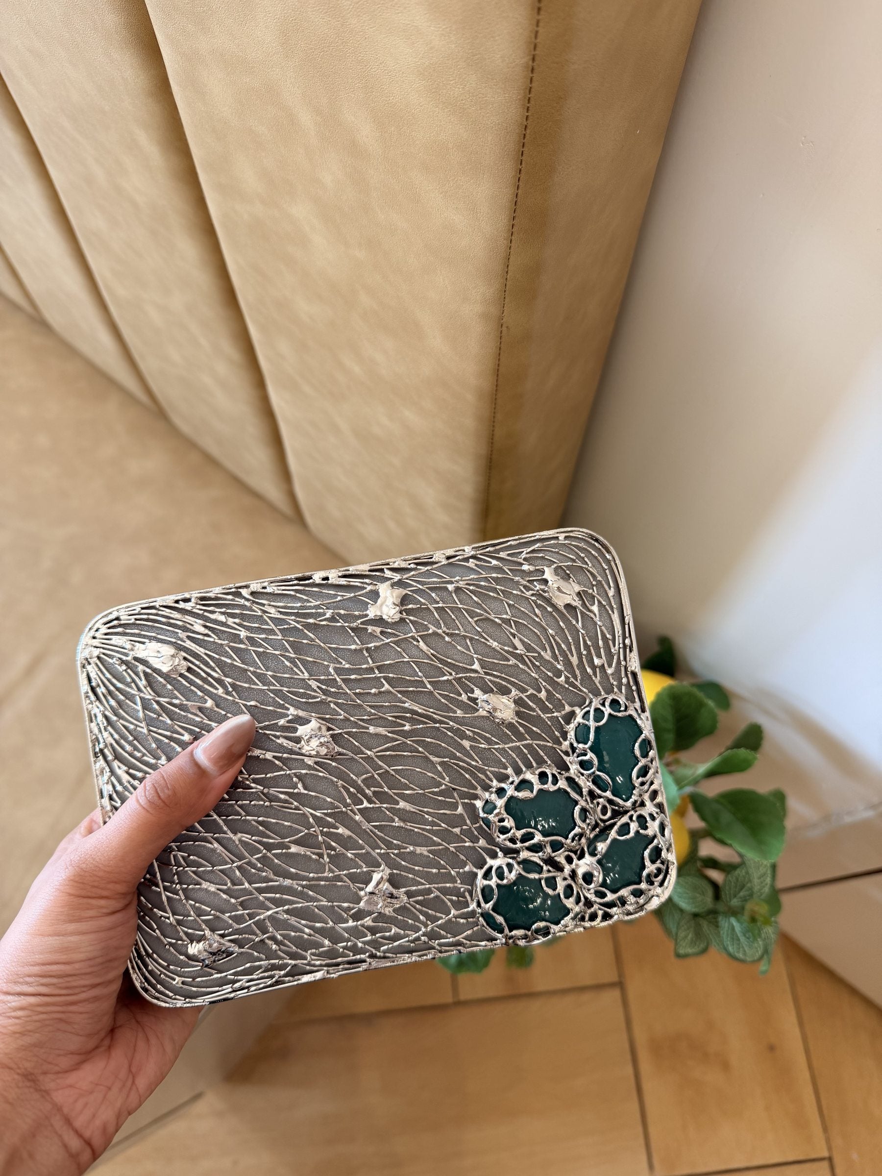 Side angle of the Molten Luxe clutch showing its structured gold borders and hinge.