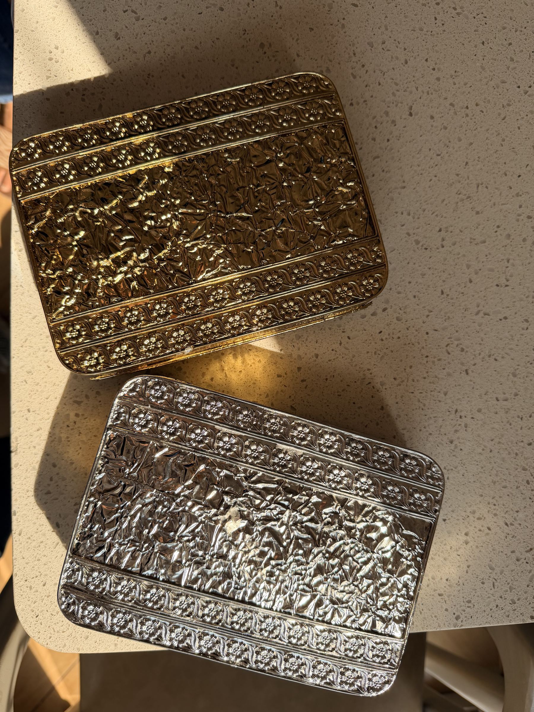 Lifestyle shot of the Molten Luxe clutch styled next to traditional gold jewelry and silk coordinates.
