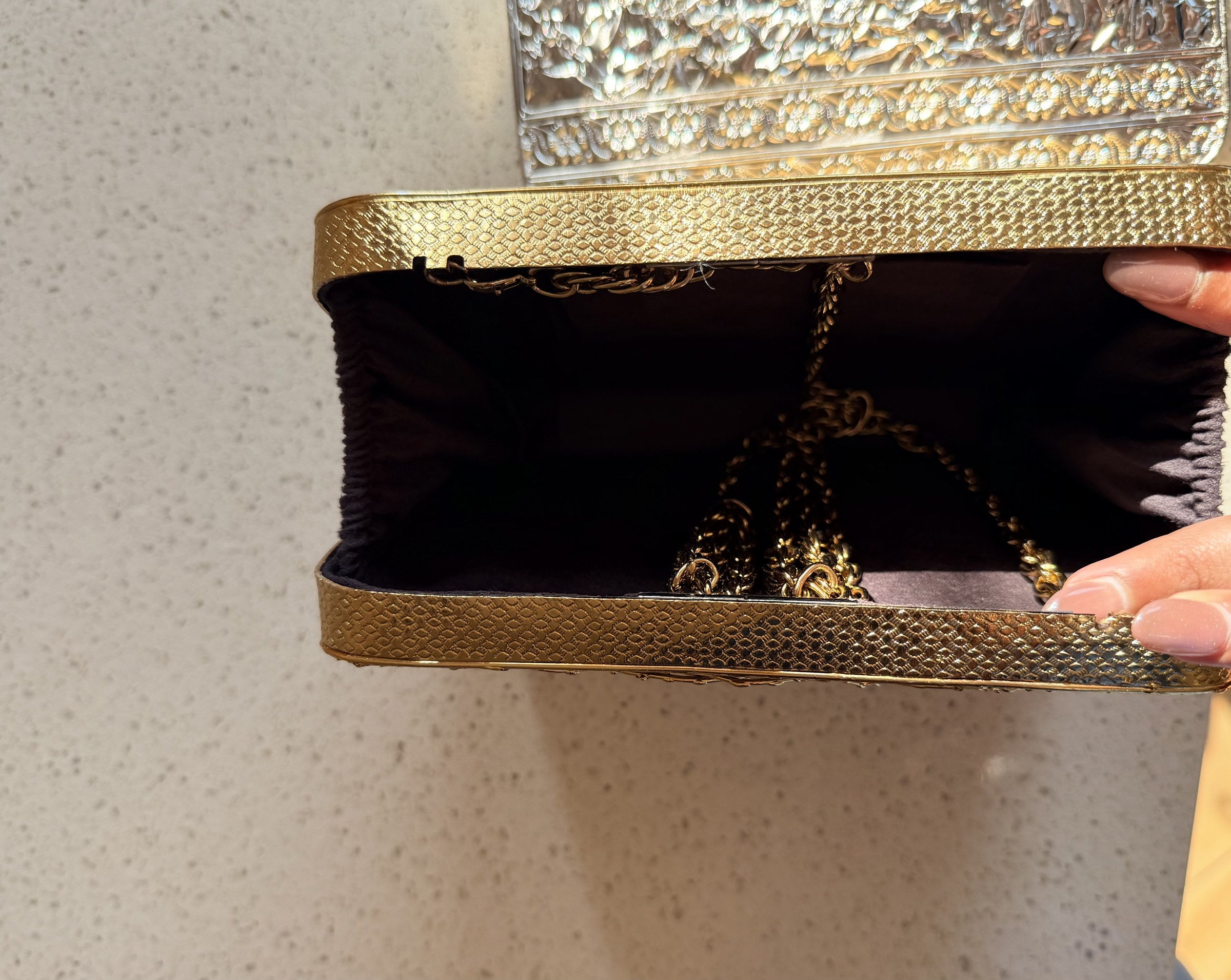 The Molten Luxe clutch held handheld, highlighting its jewel-like design and proportions.