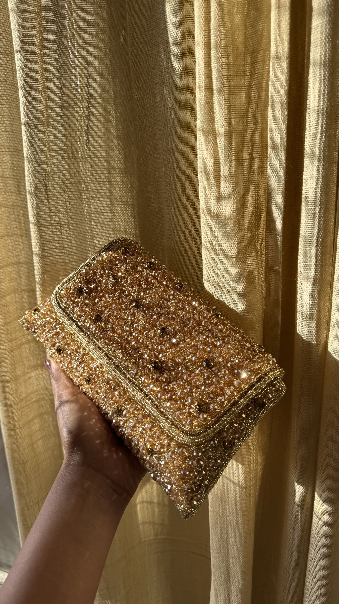 Angled view of the Moonbeam Crystal clutch with its metallic sling chain attached.