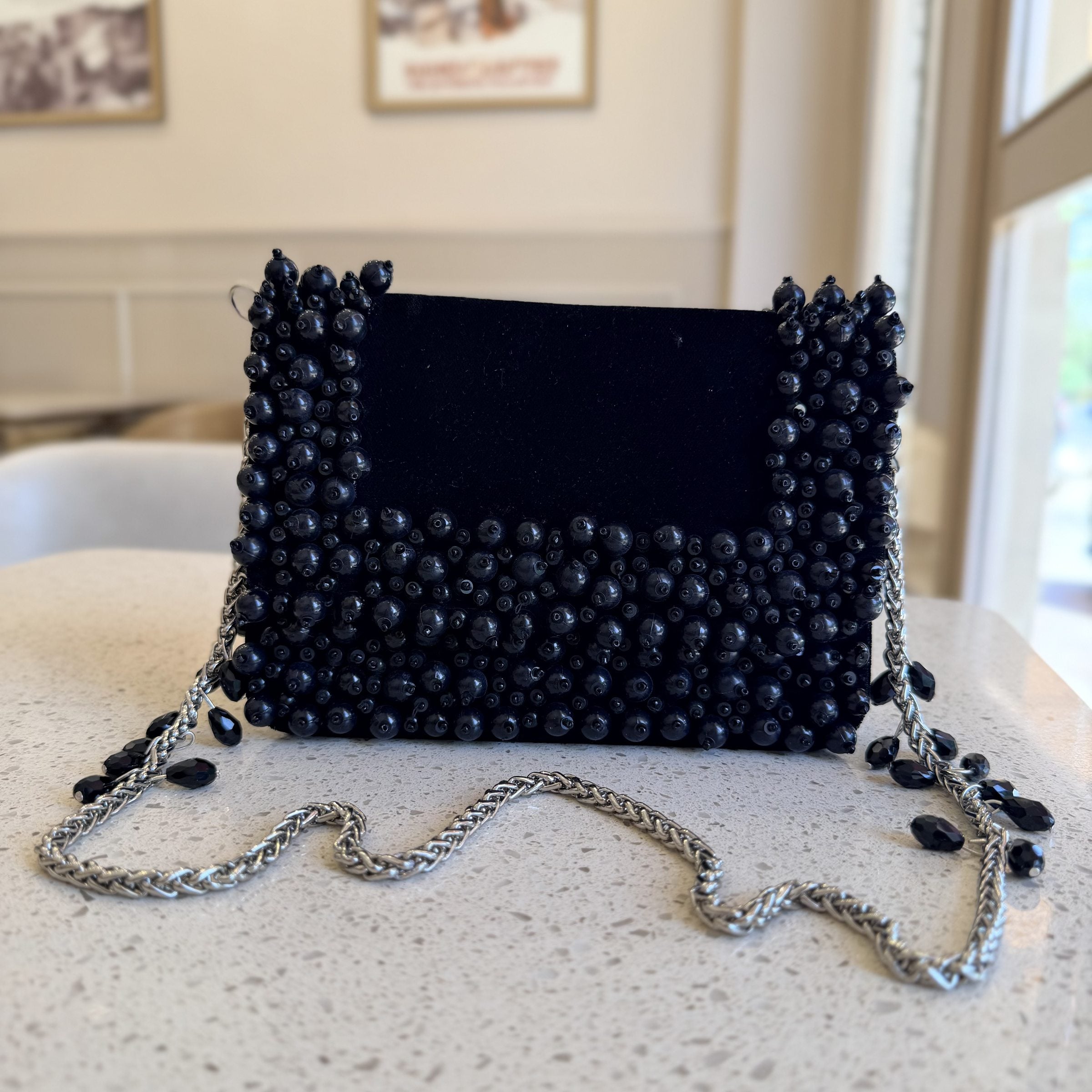 Close-up of the delicate white pearls hand-applied onto the black fabric face.