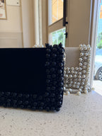 Model styling the Noir Pearl Edit clutch handheld with an elegant dress.