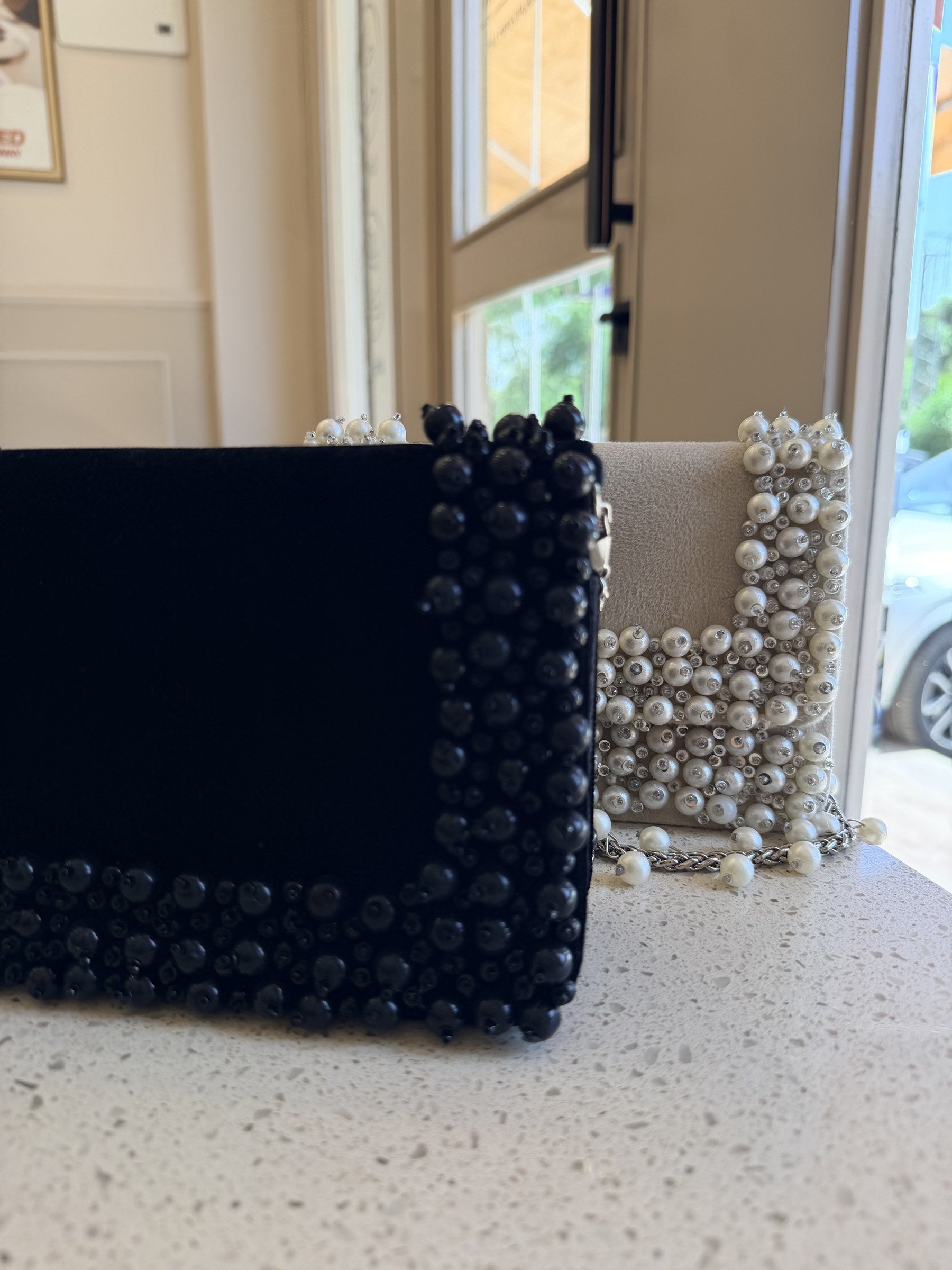 Model styling the Noir Pearl Edit clutch handheld with an elegant dress.