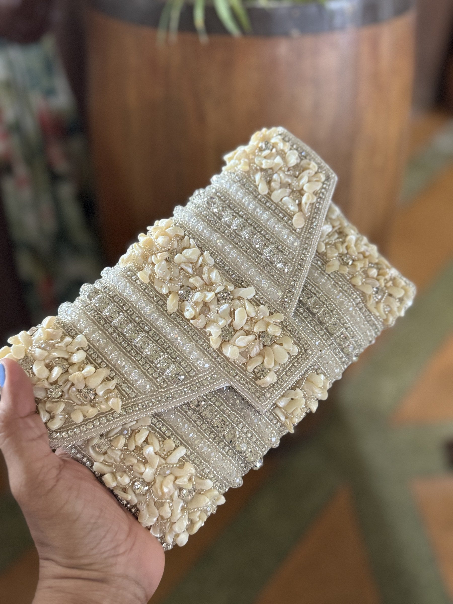 Lifestyle layout of the Riwayat Fold bag styled next to gold jewelry and bridal wedding wear coordinates.