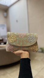 Angled view of the Rosette Flap bag with its short beaded wrist handle attached.
