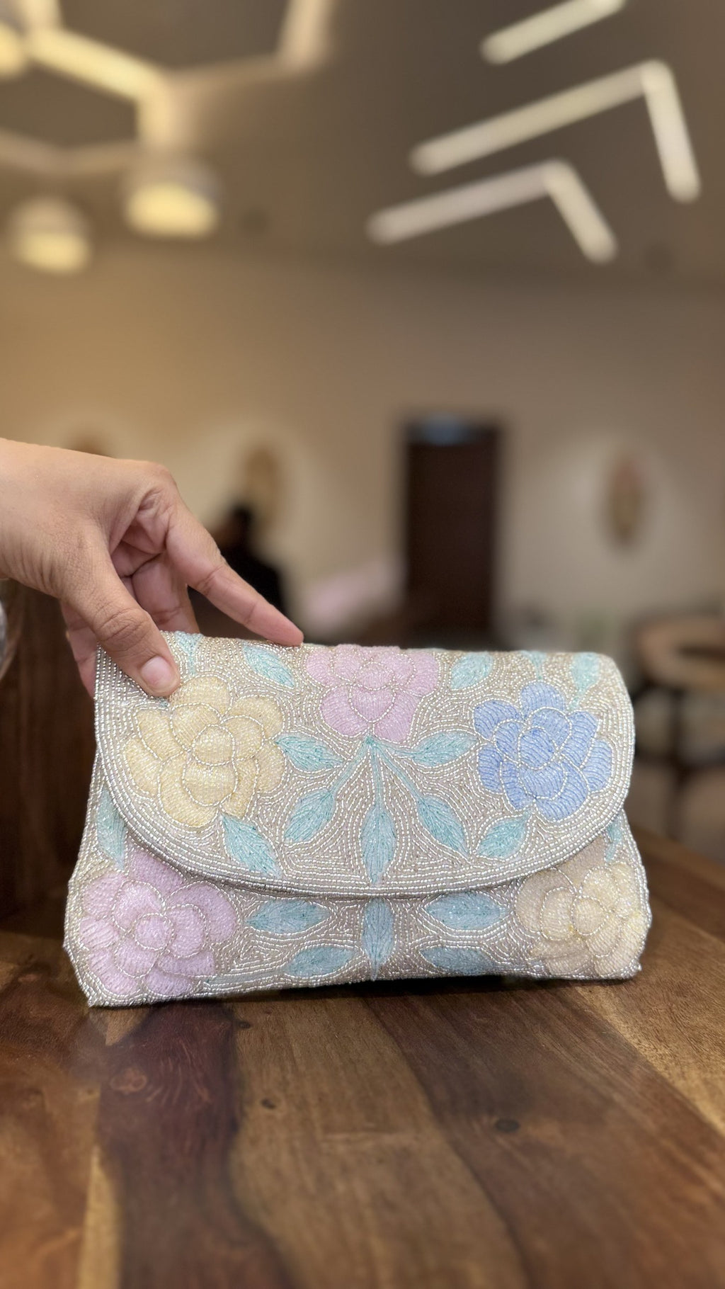 The Rosette Flap bag held by its beaded wrist strap, illustrating a sophisticated carry style.