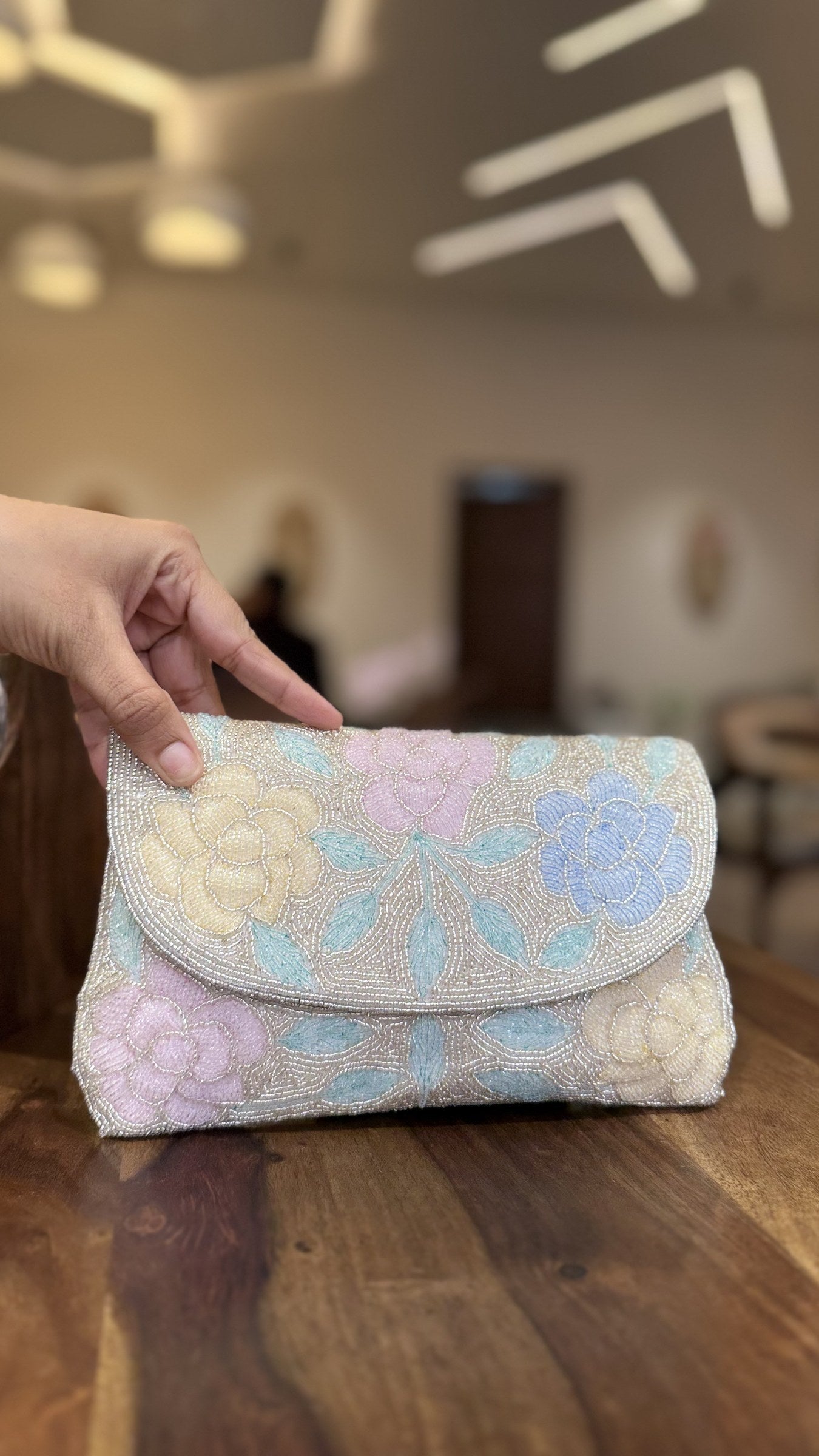 The Rosette Flap bag held by its beaded wrist strap, illustrating a sophisticated carry style.