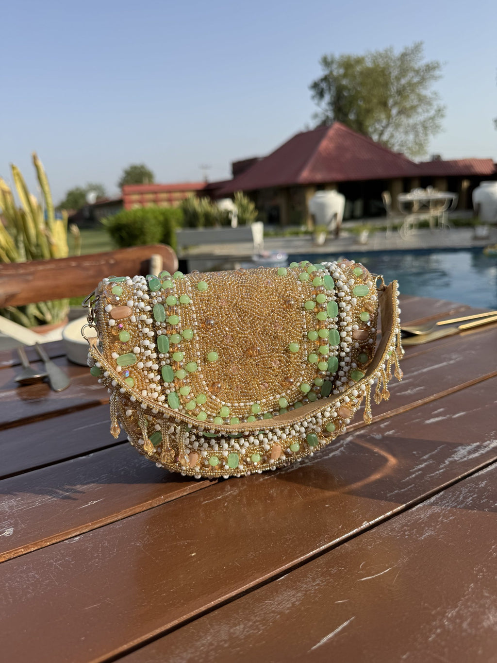 Top view of the Sage Blush clutch showing the clasp lock and handle attachment.