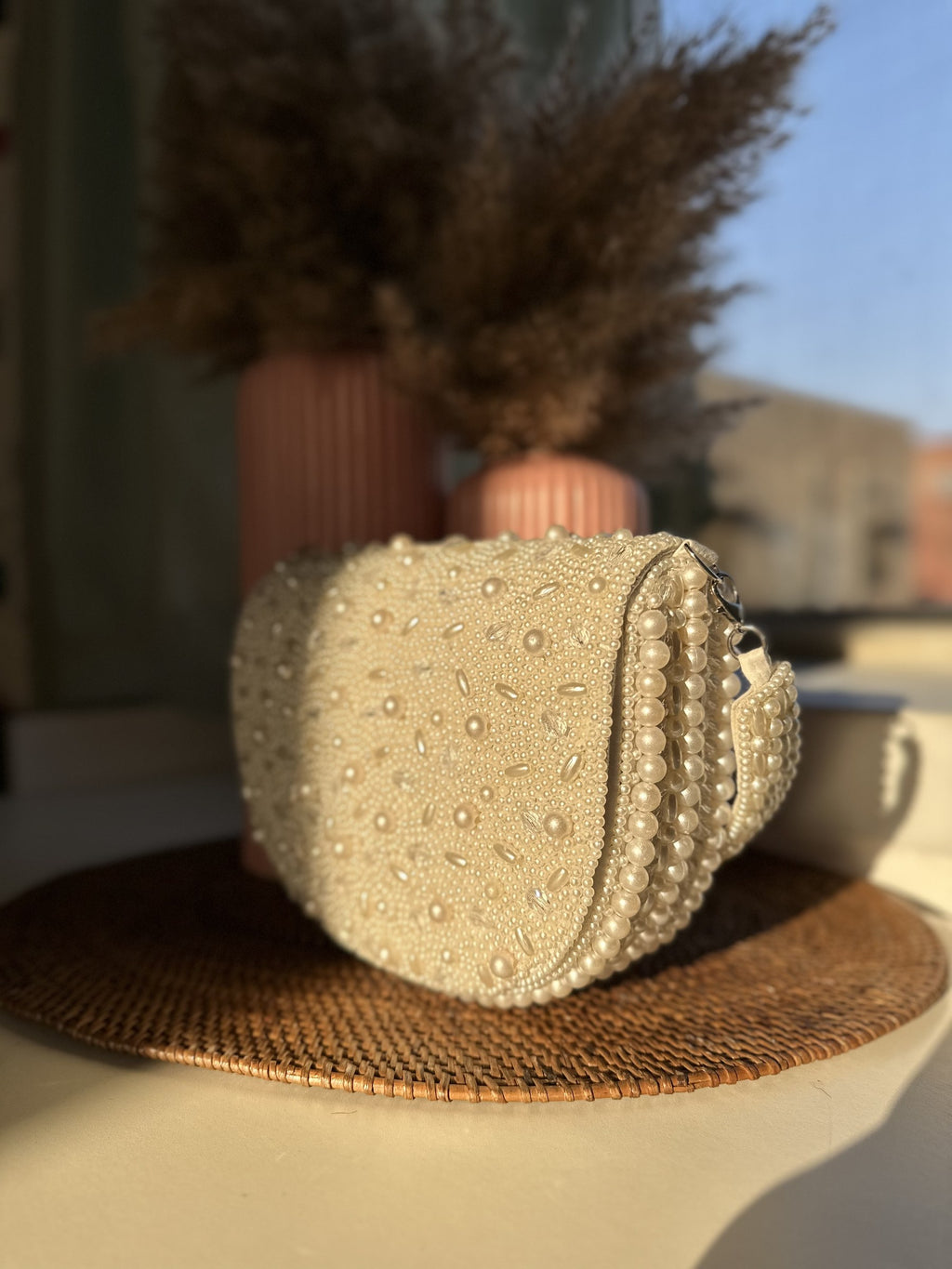 Model styling the Shukti bag handheld with a sleek white blazer outfit.
