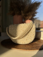 Flat lay of the Shukti bag with white sunglasses and silver jewelry.