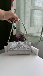 Model styling the Sunara bag handheld with an ivory resort gown.