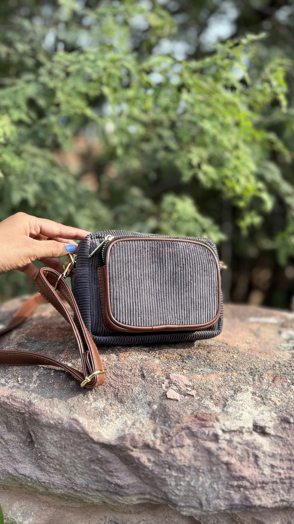 Close-up of the metal clasp connecting the corduroy shoulder strap to the bag body.
