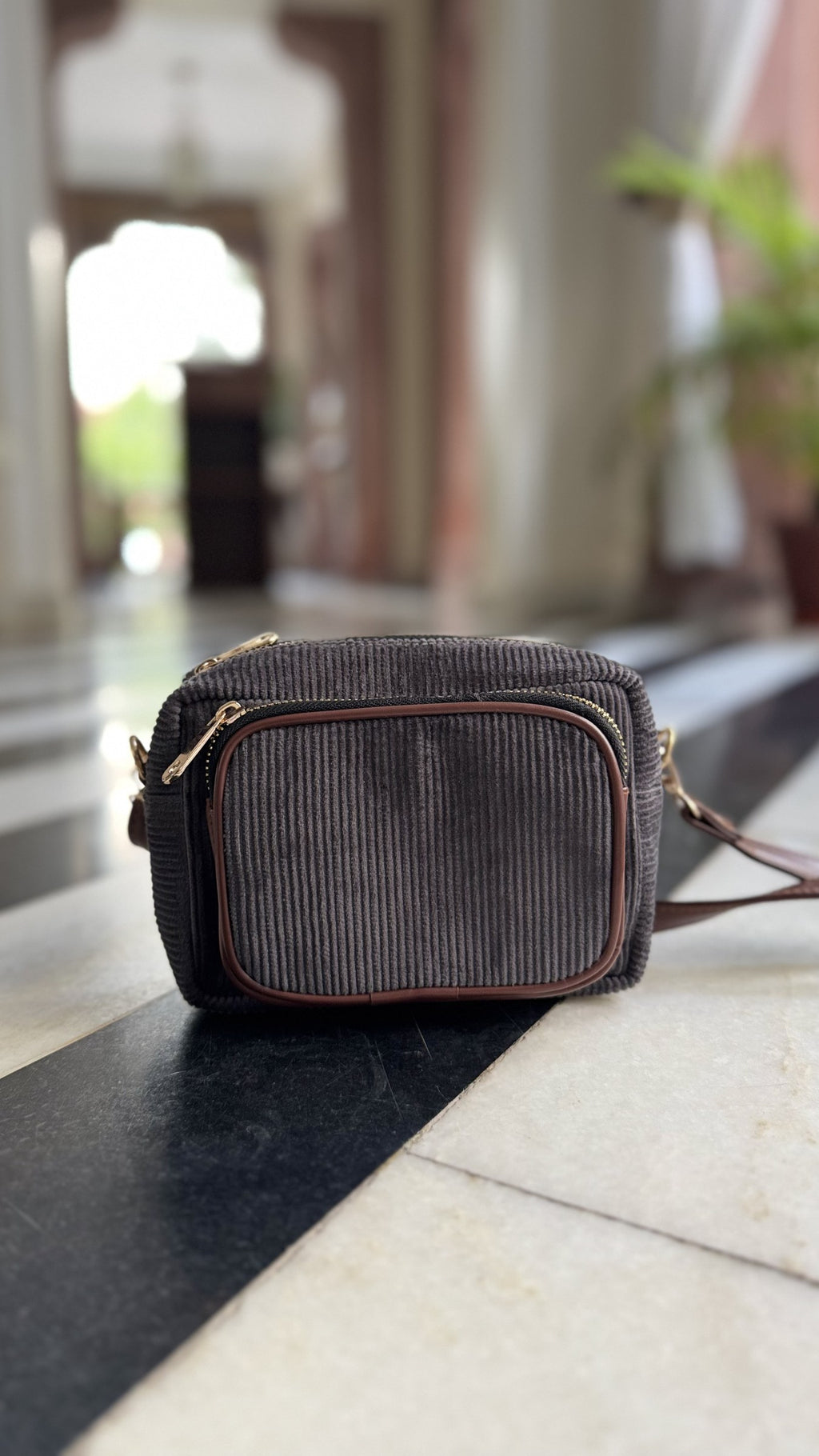 Flat lay of the Corduroy Sling bag shown with keys, sunglasses, and hand cream.
