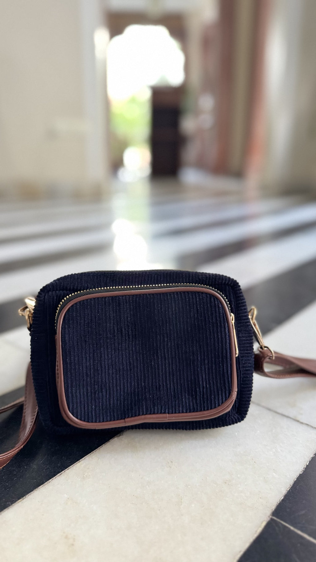 A model carrying the Corduroy Sling in hand, demonstrating its versatile wristlet grip option.