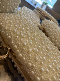 The Pearl Edit clutch displaying its all-over shimmering white pearls and gold-tone clasp.