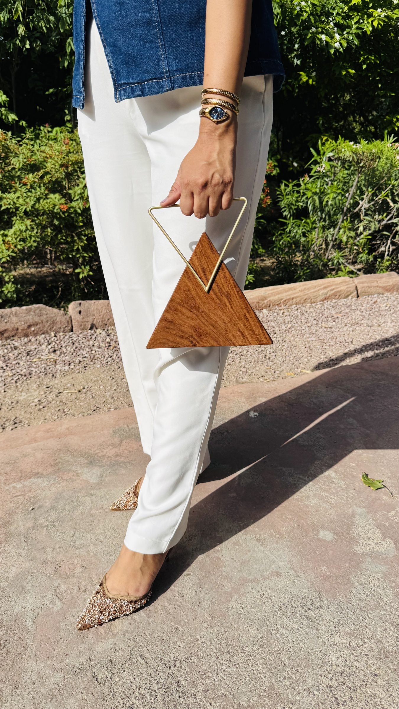 Trikon Luxe triangular wooden clutch displaying its unique geometric shape, sheesham grain, and brass push lock.