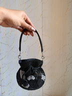 The Veloura Mini potli held by its beaded wrist strap, showing wristlet carry style.