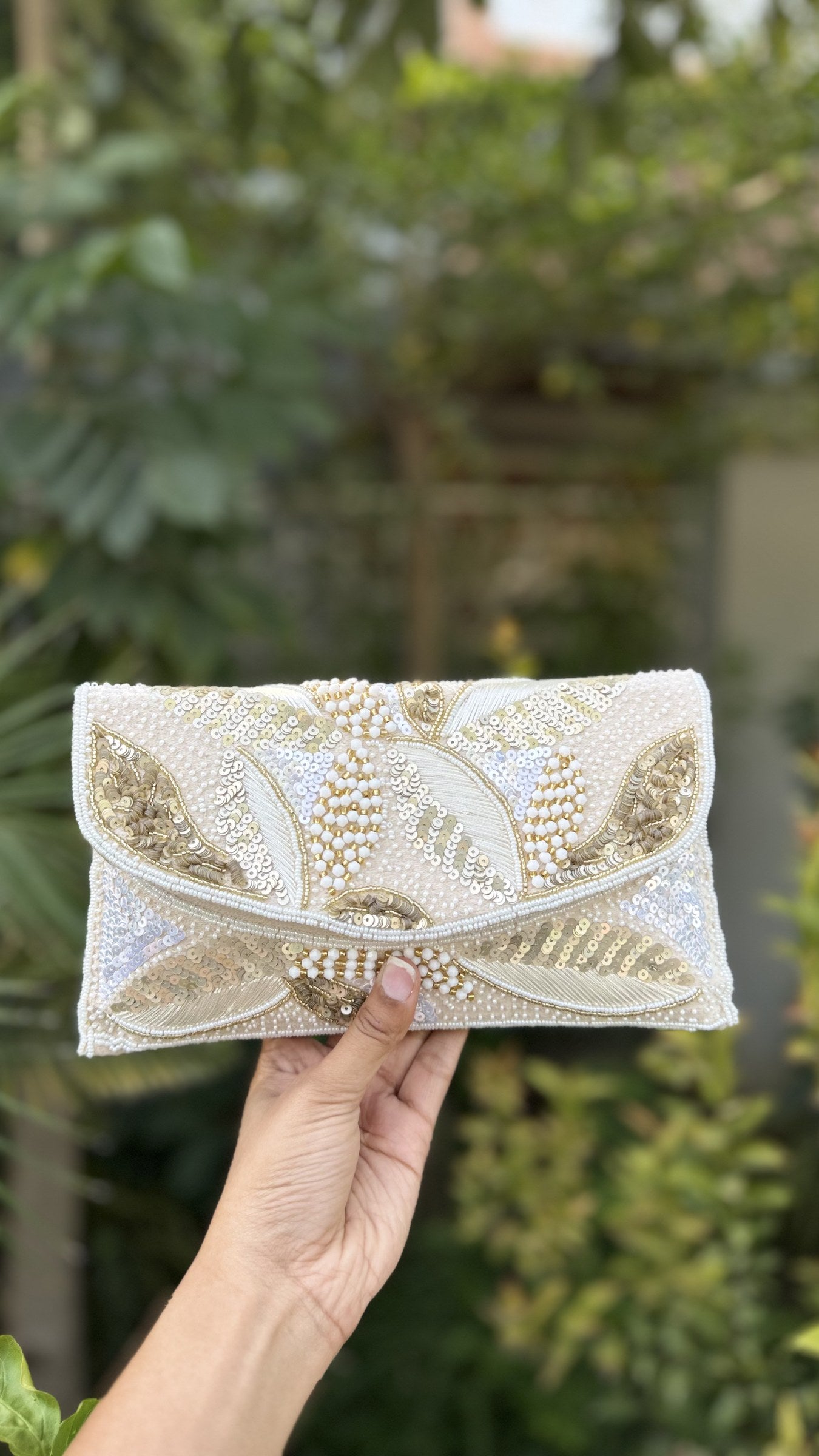 Zaraa Blossom flap bag displaying its pink and green floral embroidery and gold-tone sling chain.